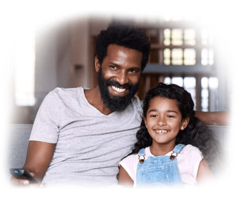 A smiling man and a young girl watch TV together